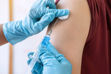 Doctor making injection vaccination patient to prevent pandemic of the disease, flu or influenza virus in clinic