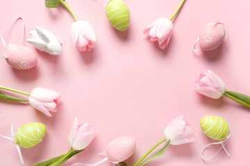 Easter frame of fresh pink flowers, colorful eggs and bunny on pink. Top view, copy space. Happy Easter holiday. Greeting card.