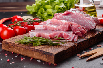 Fresh pieces pork ready to cook on a dark background in the kitchen