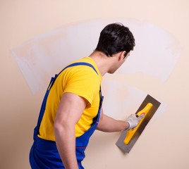 Young contractor employee applying plaster on wall