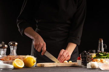 Chef cooks by chopping garlic. Against the background of vegetables. Cooking, tasty and wholesome food.