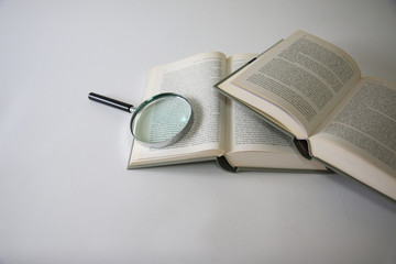 Lente d’ingrandimento con libri aperti, isolati su fondo bianco, particolare