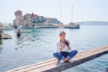 Tourism concept. Young traveling woman enjoying the view of Kastel Gomilica Castle sitting near the sea on Croatian coast.