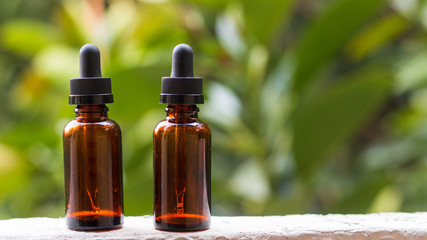 Pair of empty droppers in the foreground in front of nature background. healthy concept. medicine containers. bottles for essential oils