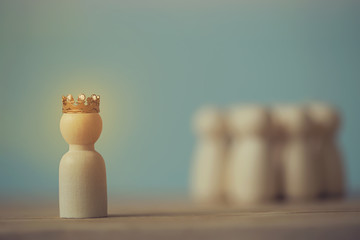 Successful business team leader concept: Wooden figures of man and people donned the crown standing...