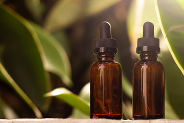Pair of empty droppers in the foreground in front of nature background. healthy concept. medicine containers. bottles for essential oils