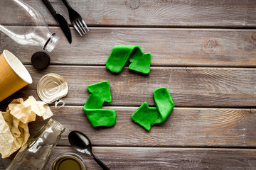 Recycle concept. Green arrows icon among waste on dark wooden background top-down copy space