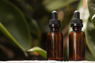 Pair of empty droppers in the foreground in front of nature background. healthy concept. medicine containers. bottles for essential oils