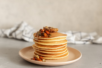 Stack of delicious pancakes with chocolate, honey, nuts and slices of banana on plate and napkin on wooden background