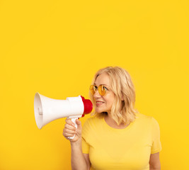 Naklejka premium Woman with megaphone isolated in the yellow studio