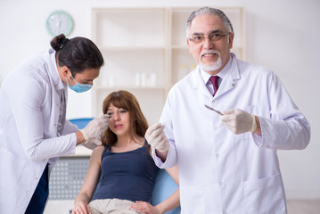 Two male doctors and young woman in plastic surgery concept