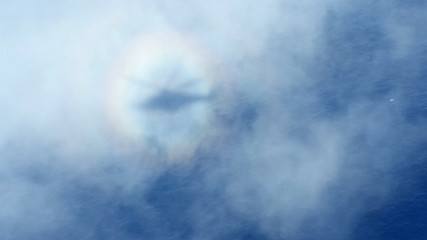 Silhouette helicopter in the cloud. Helicopter shadow with a rainbow seen through clouds over the  Ocean. 