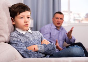 Fototapeta na wymiar Offended boy and angry father having quarrel at home