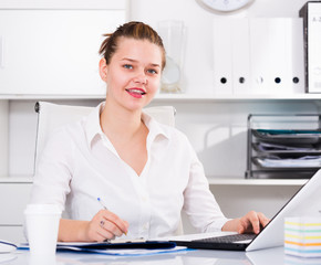 Female is working with documents and laptop