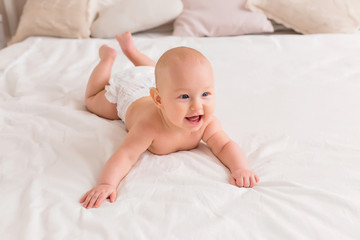 baby boy smiling and lying on a light bed at home