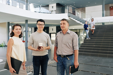 Obraz premium Multi-ethnic smiling successful business team standing in office hall and looking at camera