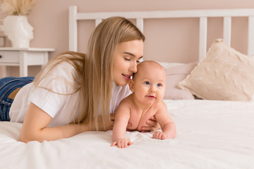 young mother hugs baby in bed at home