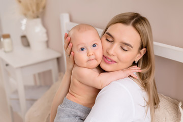 young mother hugs baby in bed at home