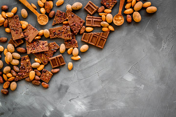 Sweets frame. Broken chocolate slices and nuts on grey stone background top-down copy space