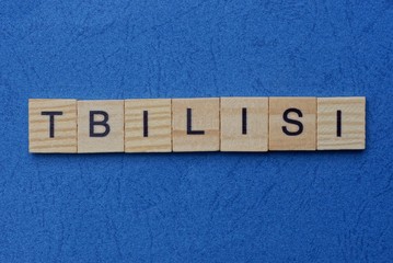 gray word tbilisi from small wooden letters on a blue table