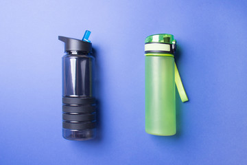 black and green sport plastic bottles lying on blue colored paper background