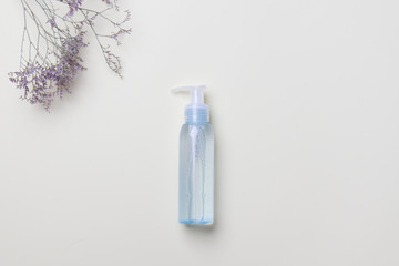 blue cosmetic bottle and flower on light yellow background