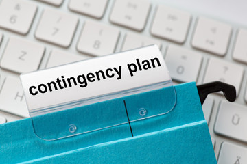 contingency plan is on a label of a blue hanging file. In the background a computer keyboard