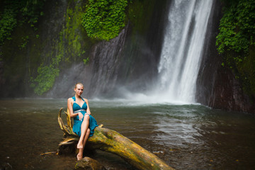 beautiful girl walks near a waterfall