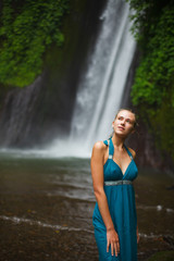 beautiful girl walks near a waterfall