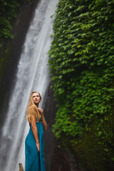 beautiful girl walks near a waterfall