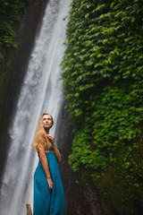 beautiful girl walks near a waterfall