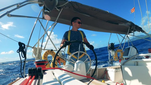 Handsome man is handling a wheel of a floating boat
