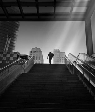 Low Angle View Of Man Walking On Steps Towards Buildings