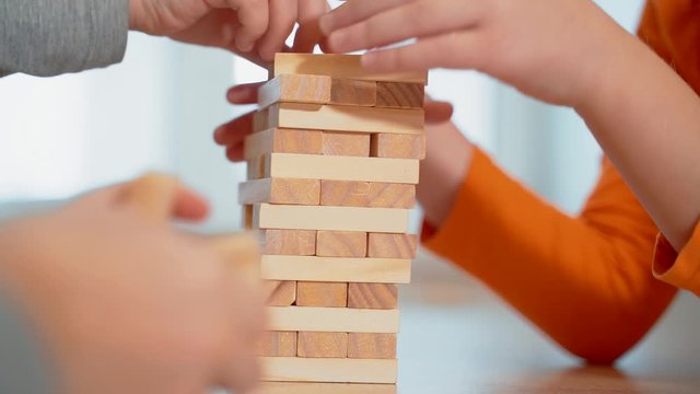 Young girls build a tower of wooden sticks. Board game.