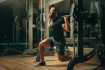 Fit man doing squats in a training machine