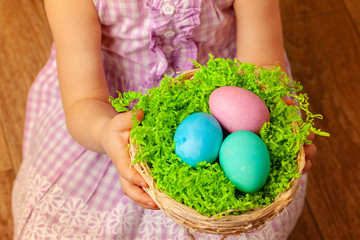 Fototapeta na wymiar Little girl holding basket with colored eggs. Easter concept