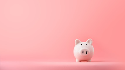white piggy Bank on a pink background with copyspace for design.