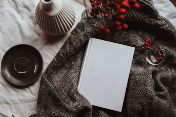 Winter autumn mock up with white book cover. Greetings card new year book mockup with red rowan berries over gray wool plaid. White book cover winter cozy mock-up.Warm festive rowan tree backdrop.