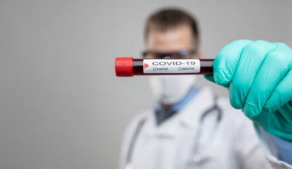 Doctor wearing respiratory mask and holding the Coronavirus blood sample