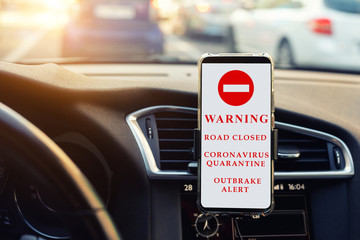 Modern smartphone device gadget mounted phone holder at car dashboard. showing traffic information message temporary road closed sign.Coronavirus outbrake quarantine alert info. Pandemia prevention