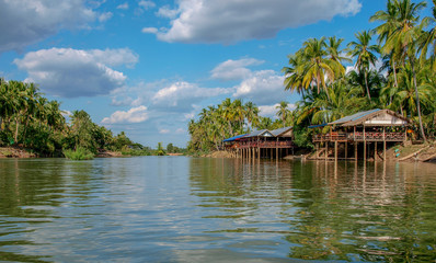 Fototapeta na wymiar Tropische Flusslandschaft der 4000 Inseln im Mekong in Laos mit Küste einer Insel und traditionellen Häusern