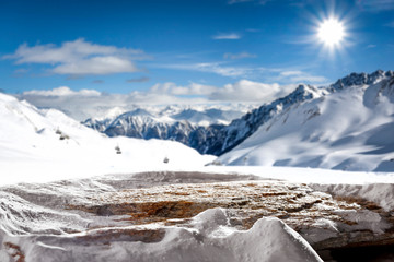 Stone background cover of snow and blurred landscape of mountains. 