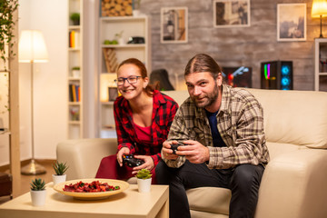 Gamers couple playing video games on the TV with wireless controllers in hands