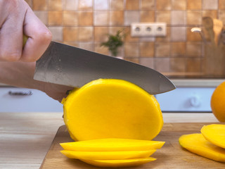 Woman cutting mango by knife on the kitchen - Powered by Adobe