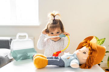 Baby toddler girl playing with doctor's kit and doll toys