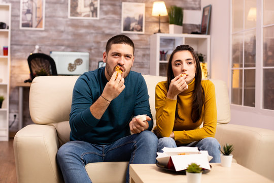 Young Couple Eating Fried Chicken In Front Of The TV