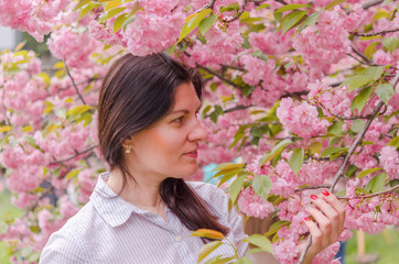 A young Caucasian girl enjoys the aroma and beauty of cherry blossoms.