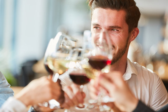 Mann beim Anstoßen mit einem Glas Wein