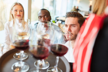 Kellnerin serviert Gästen Rotwein auf Tablett