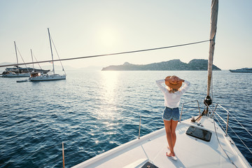 Luxury travel on the yacht. Young happy woman on boat deck sailing the sea. Yachting in Greece. - obrazy, fototapety, plakaty